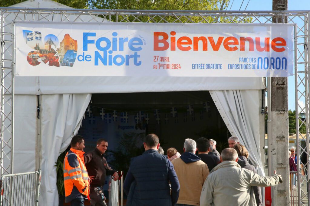 Entrée de la Foire de Niort avec des visiteurs, signalée par une bannière Bienvenue. Événement du 27 avril au 1er mai 2024.
